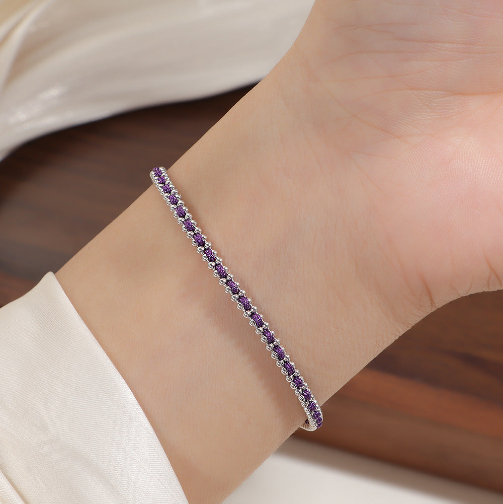 Silver and purple cord bracelet worn on the wrist