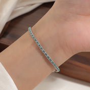 Silver and teal cord bracelet worn on the wrist
