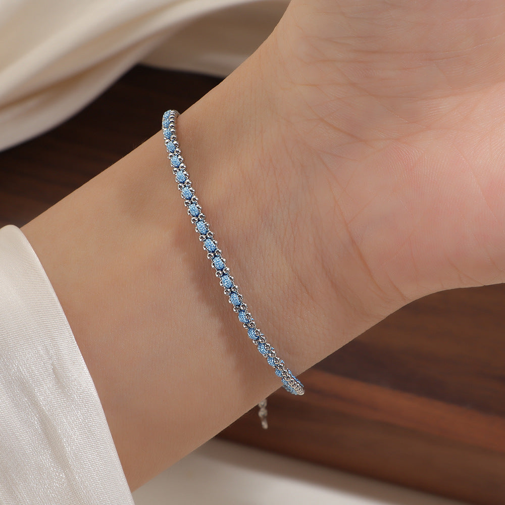 Silver and light blue cord bracelet worn on the wrist