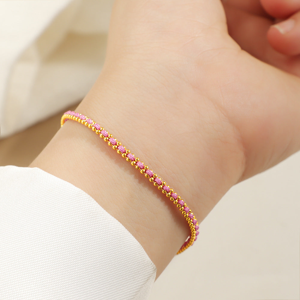 Gold and pink cord bracelet worn on the wrist