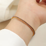Gold and purple cord bracelet worn on the wrist