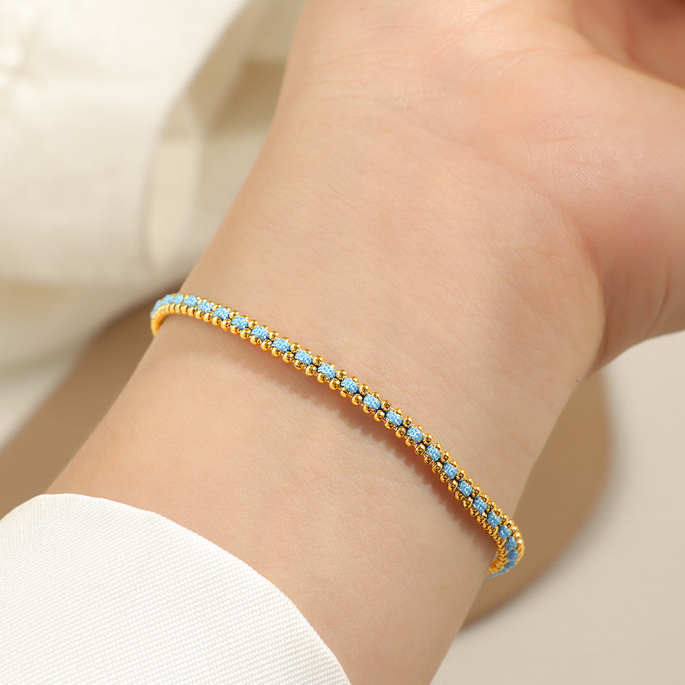 Gold and light blue cord bracelet worn on the wrist