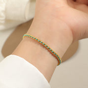 Gold and teal cord bracelet worn on the wrist