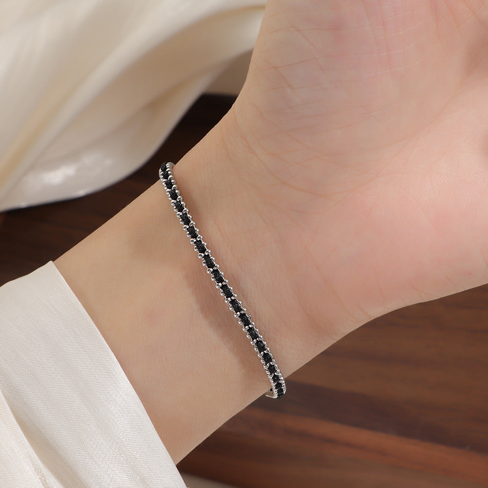 Silver and black cord bracelet worn on the wrist