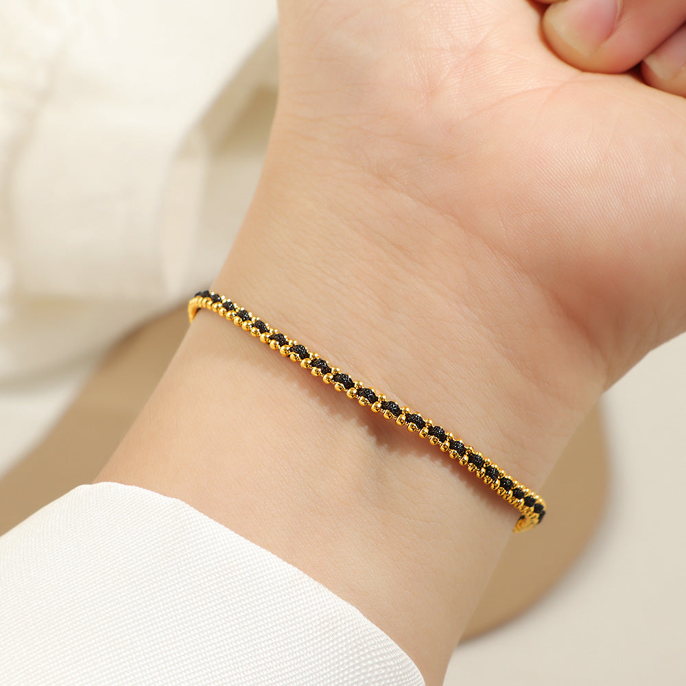 Gold and black cord bracelet worn on the wrist