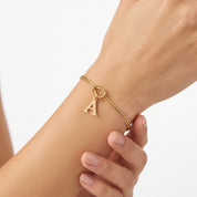 Gold letter initial bracelet with a knot charm worn on the wrist