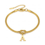 Gold initial bracelet with letter A charm laid flat on white