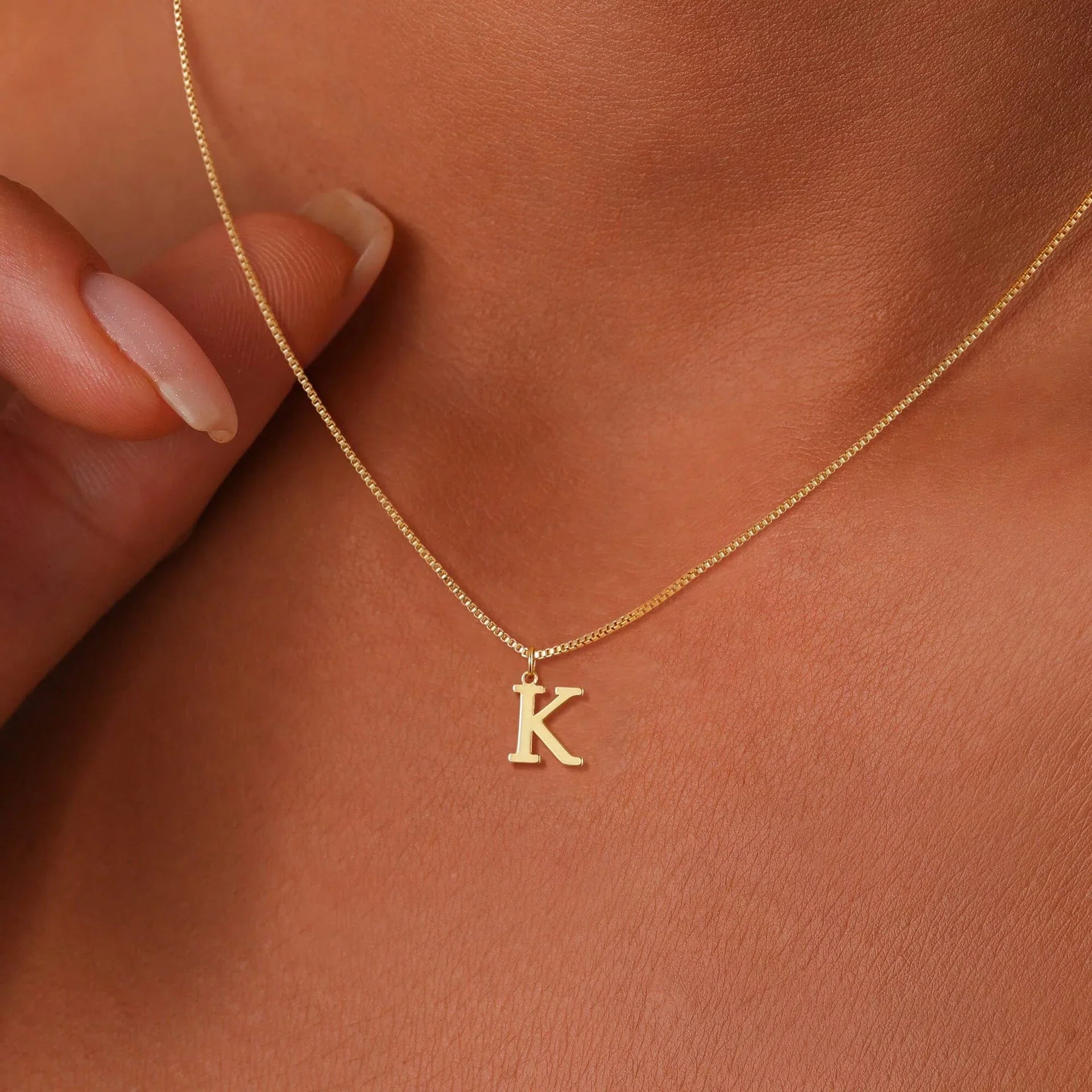 Gold initial necklace with a letter K pendant on the collarbone