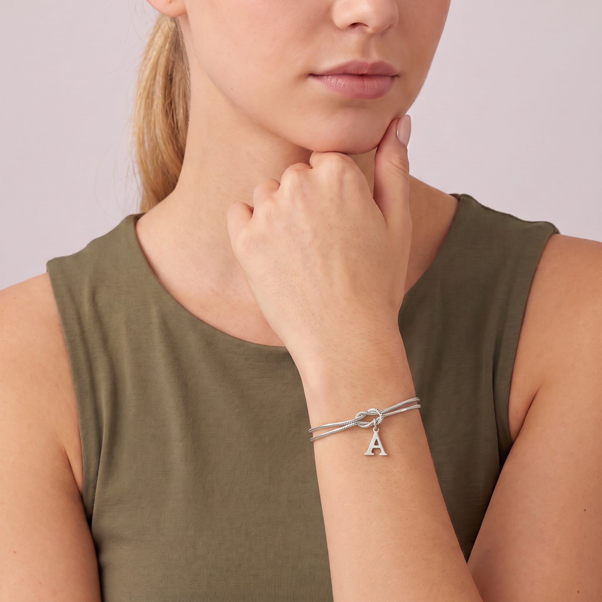 Silver initial bracelet worn with the chin resting on the hand