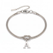 Silver initial bracelet with letter A charm laid flat on white