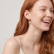 Gold teardrop huggie earring in a laughing portrait