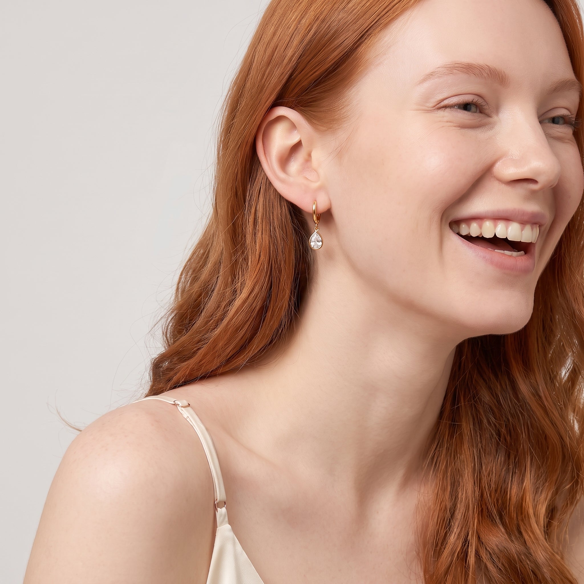 Gold teardrop huggie earring in a laughing portrait