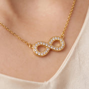 Gold pavé infinity necklace, close-up of the crystal infinity on skin