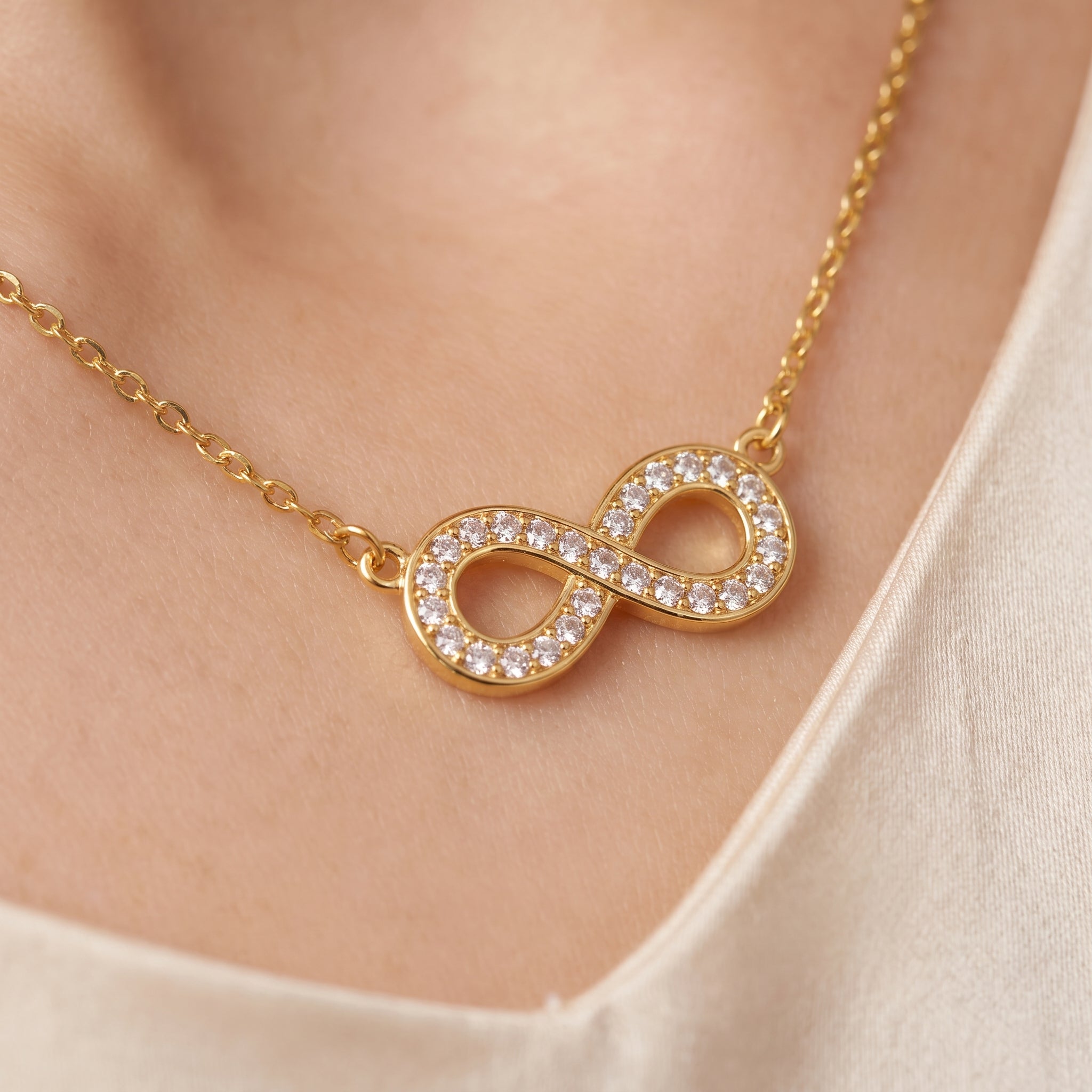 Gold pavé infinity necklace, close-up of the crystal infinity on skin