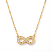 Gold pavé infinity necklace laid out on a white background