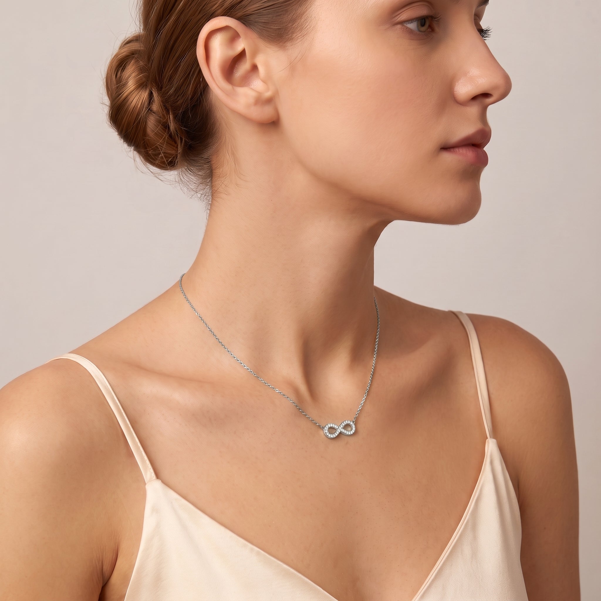 Silver pavé infinity necklace worn in a shoulder-forward profile