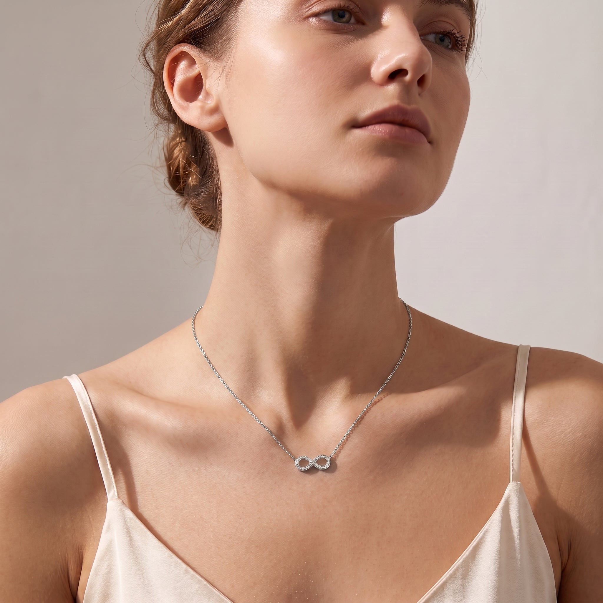 Silver pavé infinity necklace worn, seen from a low angle