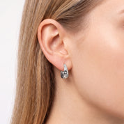 Silver star huggie hoop earring with crystals on the earlobe, close-up