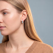 Silver star huggie earring worn with a camel sweater