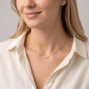 Gold sideways cross necklace worn with the head tilted down