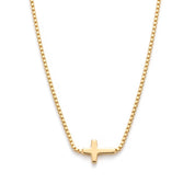 Gold sideways cross necklace laid out on a white background