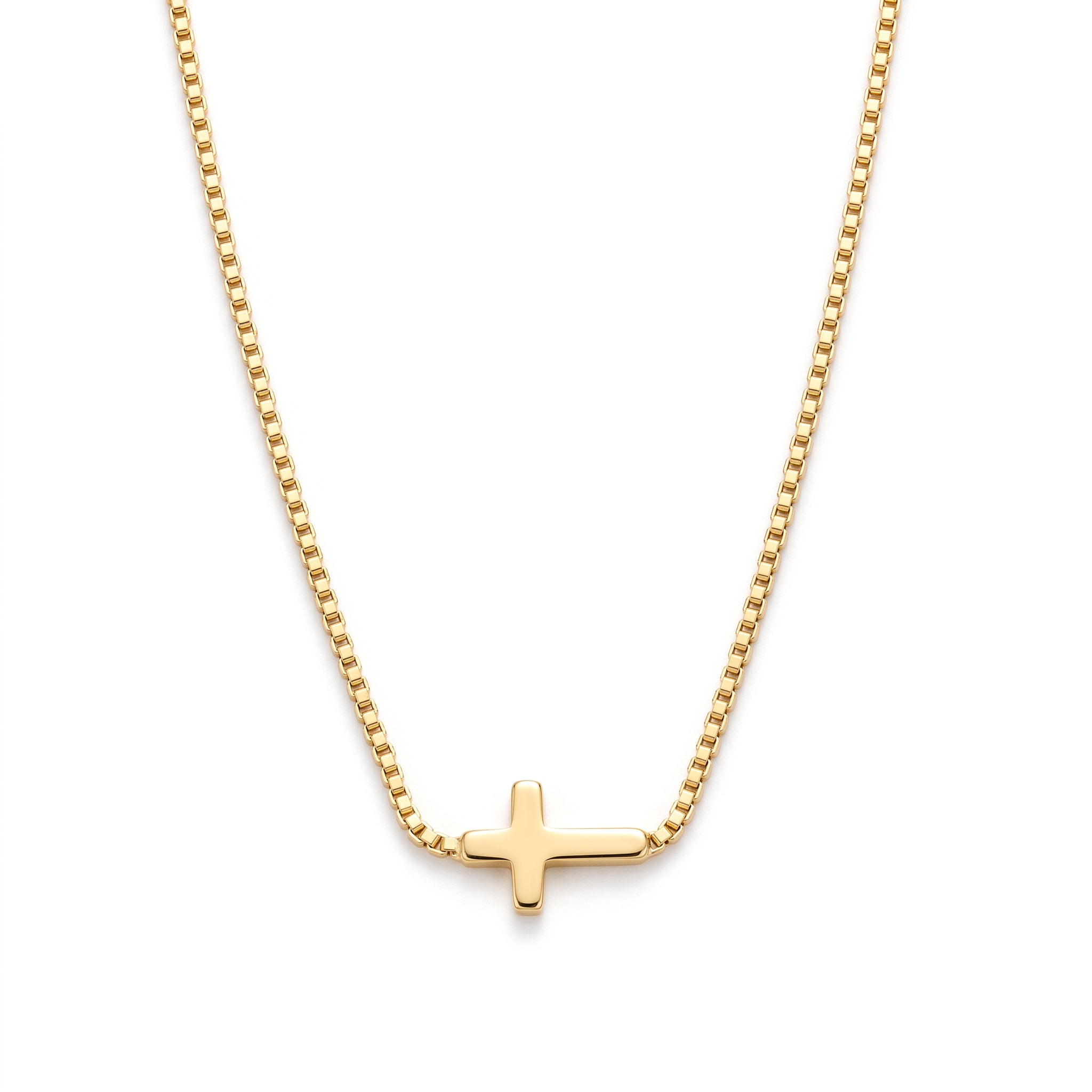 Gold sideways cross necklace laid out on a white background