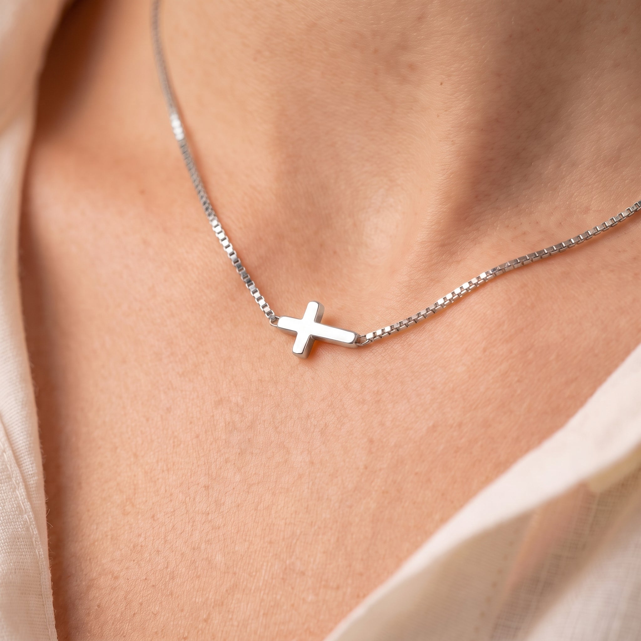 Silver sideways cross necklace, close-up of the cross on skin