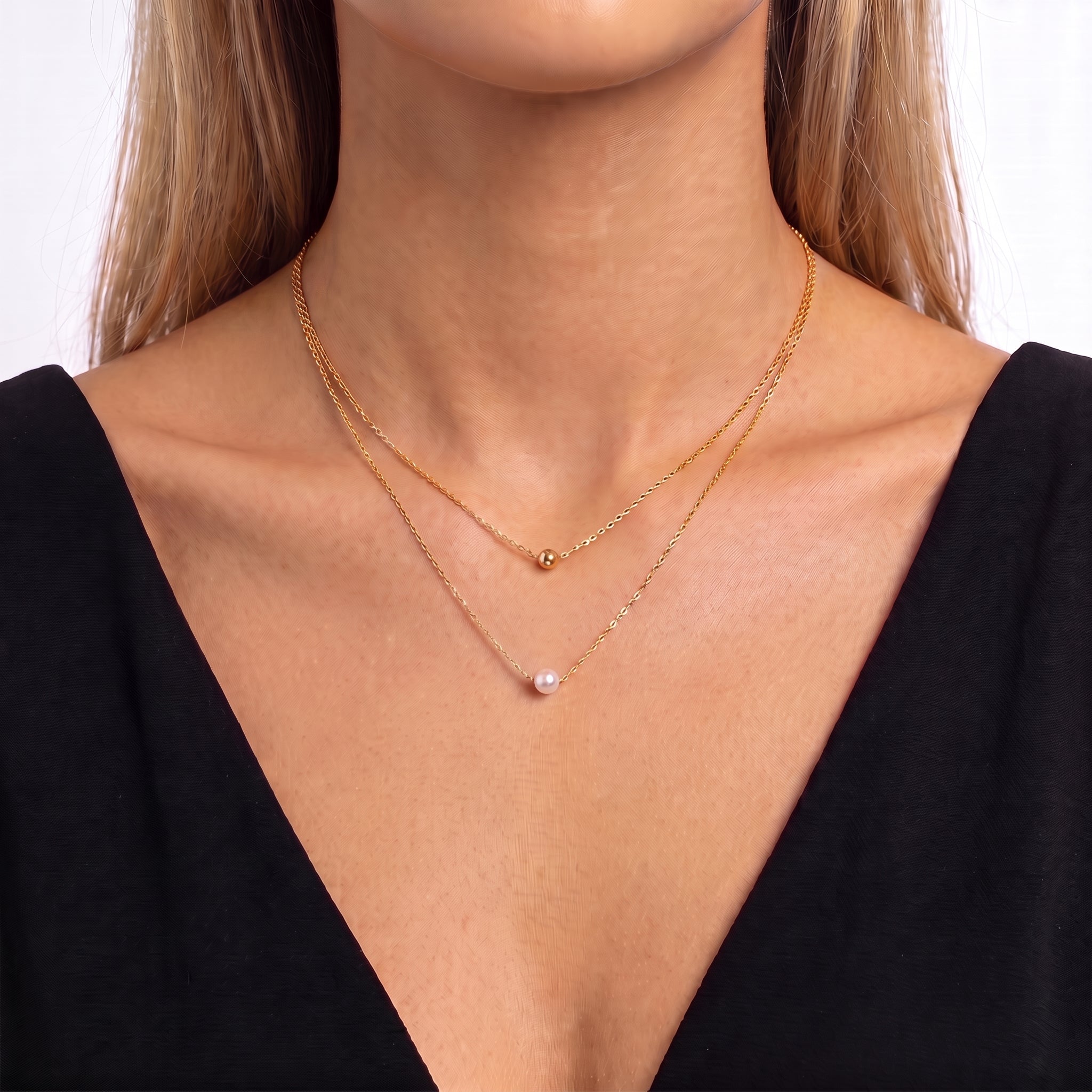Woman wearing Aveline gold layered pearl necklace with a black V-neck dress