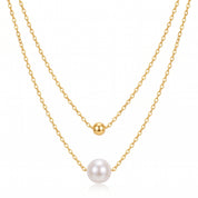 Gold double chain necklace with a small bead and single pearl on white background