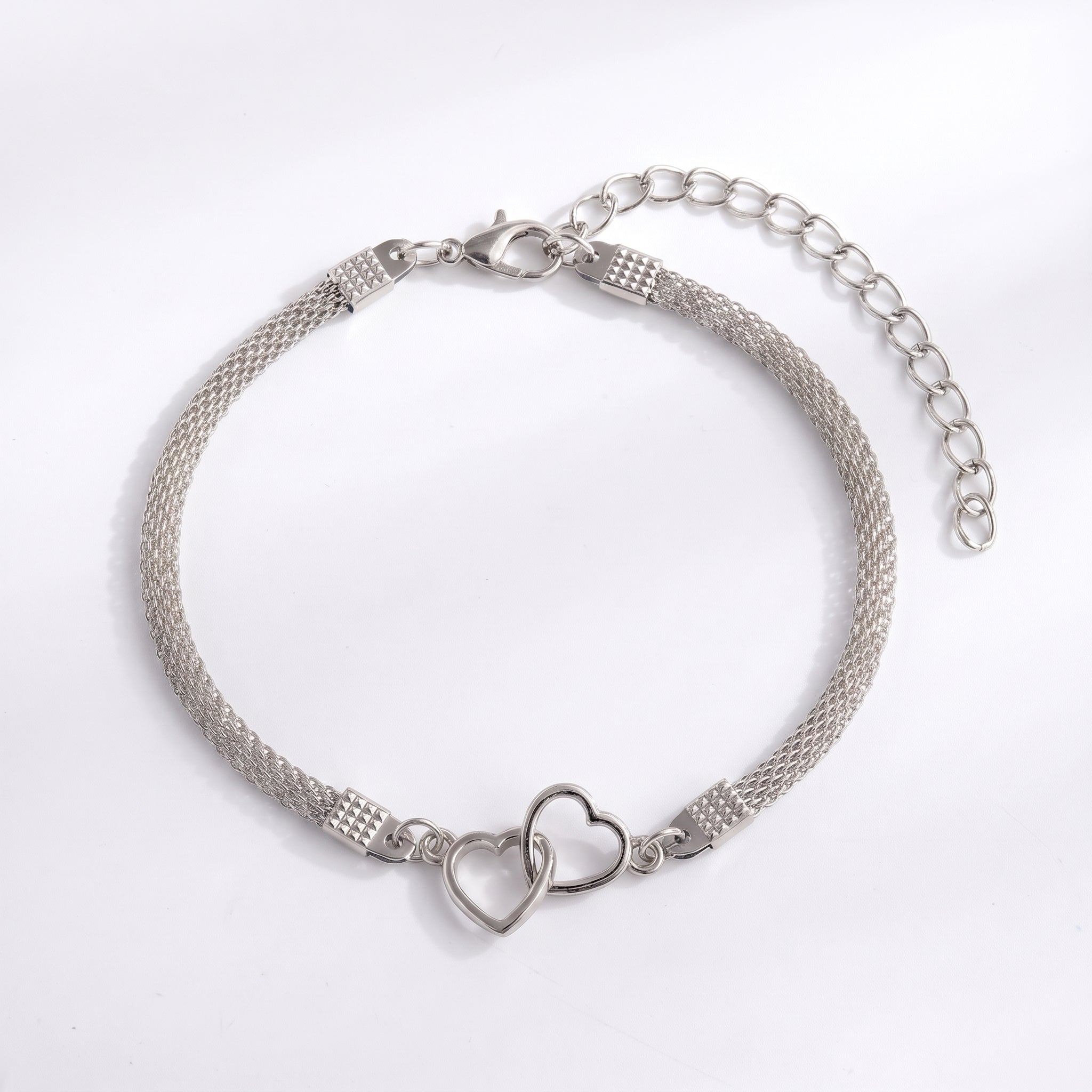 Silver double heart mesh anklet laid flat with extender on white
