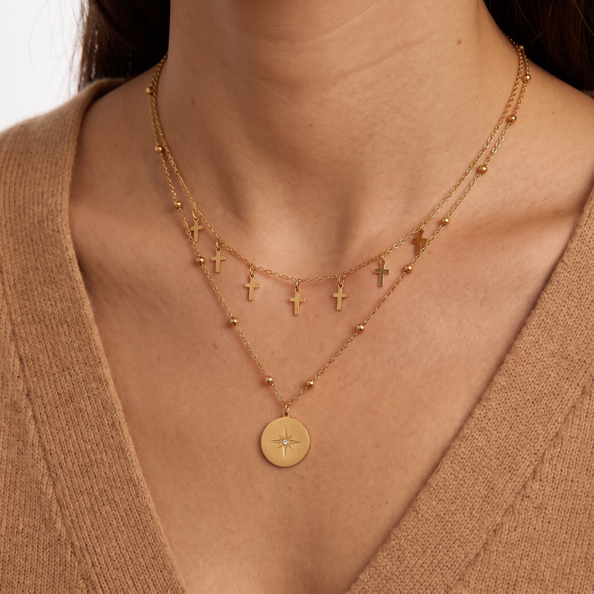 Woman wearing Celestine gold layered cross necklace with a north star coin pendant