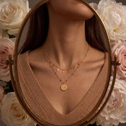Celestine necklace reflected in an oval mirror, worn with a camel V-neck sweater