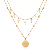 Gold cross charm chain and north star medallion on a beaded chain, white background