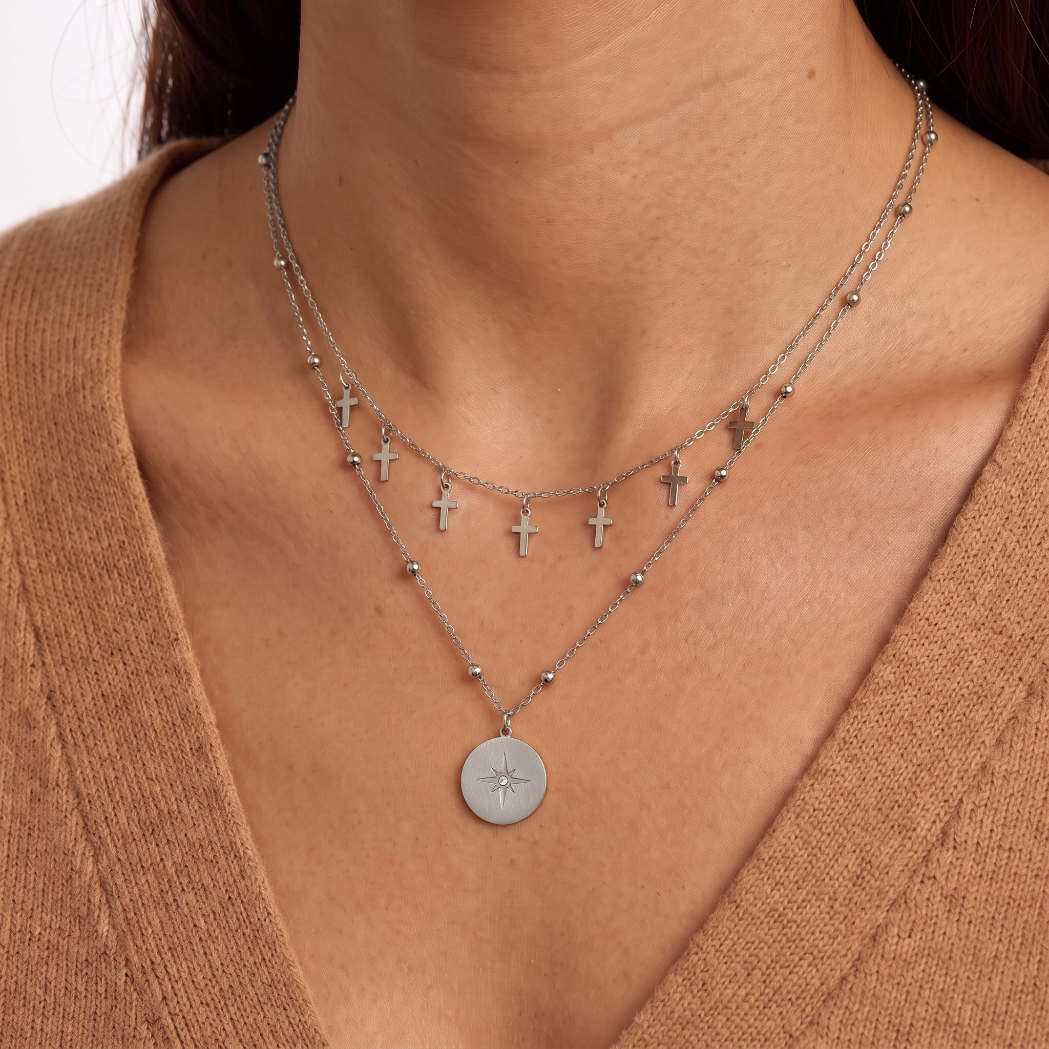 Woman wearing Celestine silver layered cross necklace with a north star coin pendant