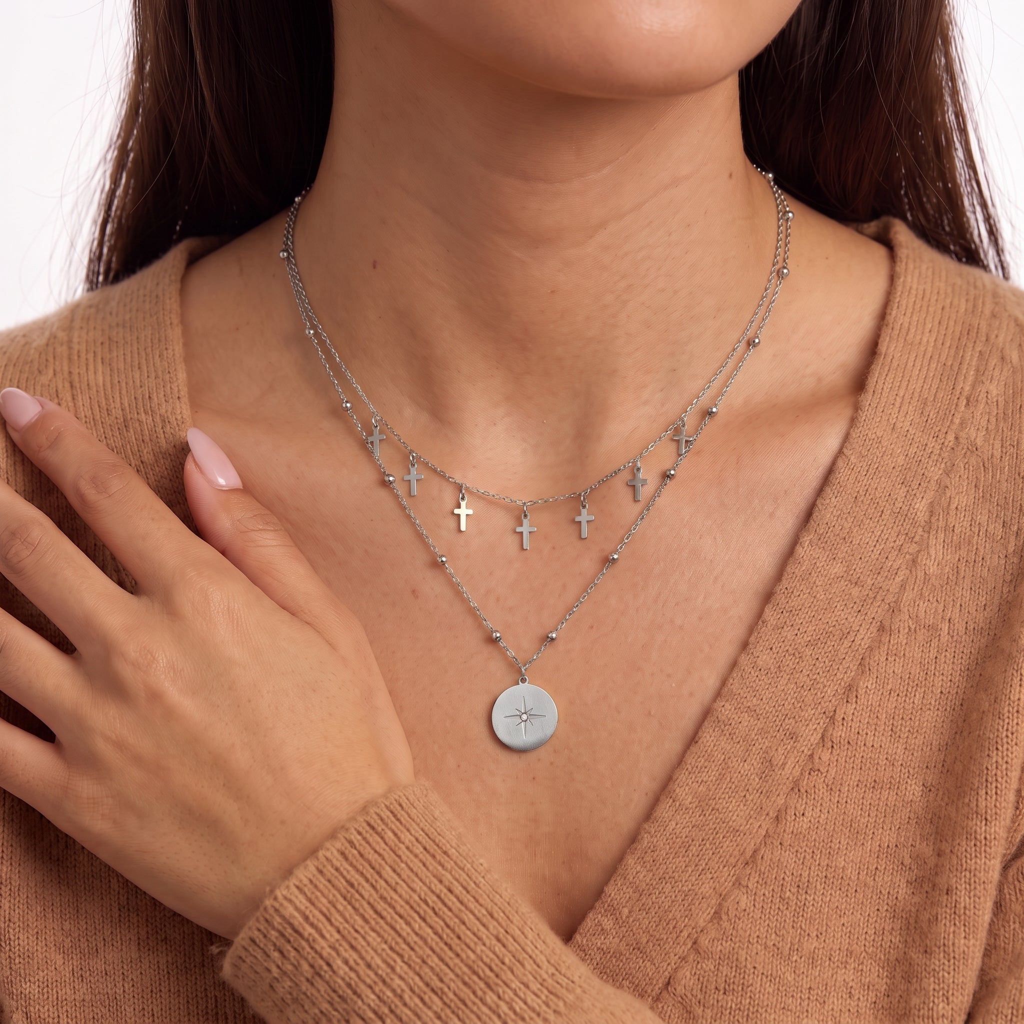 Hand at shoulder beside Celestine silver cross charm necklace and beaded chain
