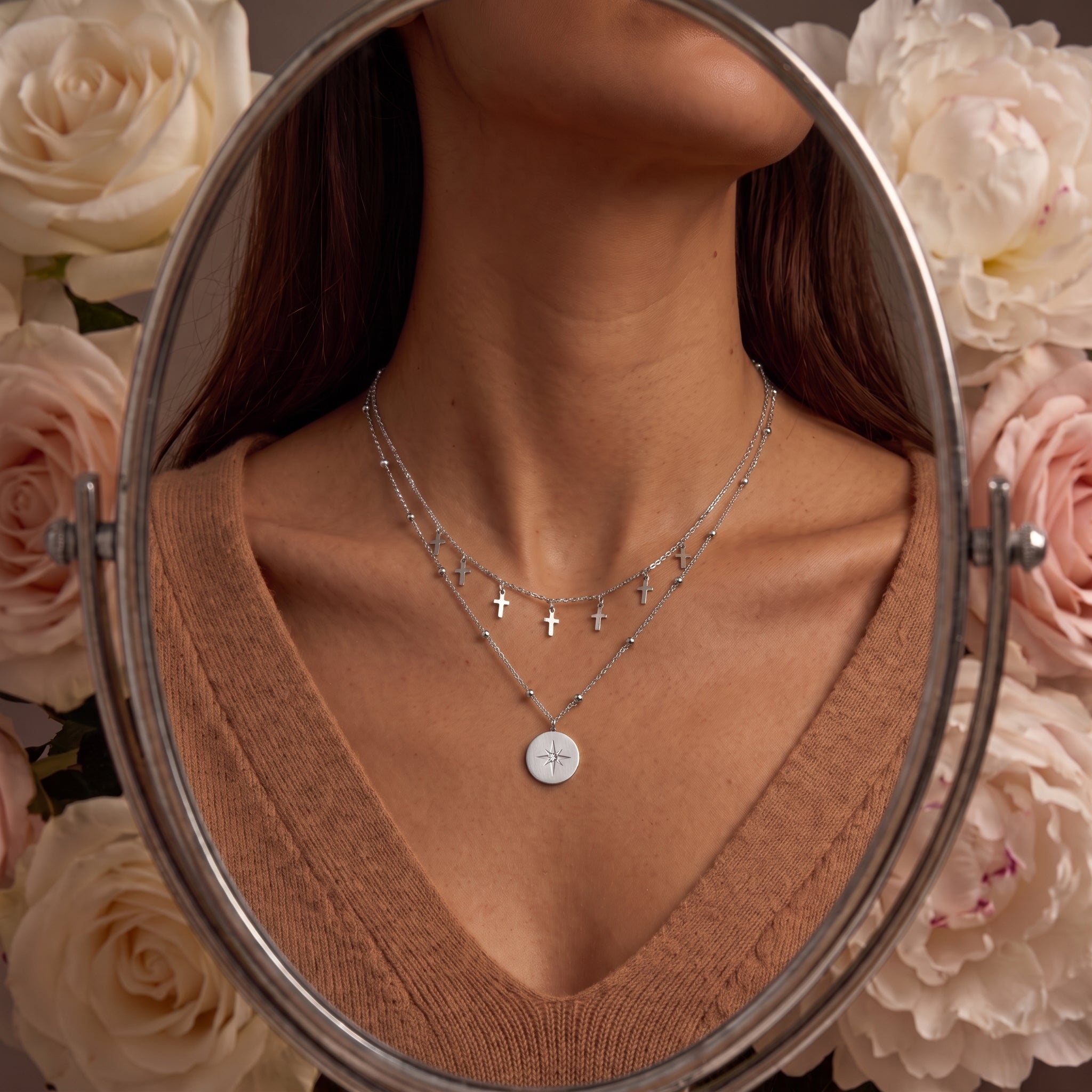 Celestine silver necklace reflected in an oval mirror, worn with a camel V-neck sweater