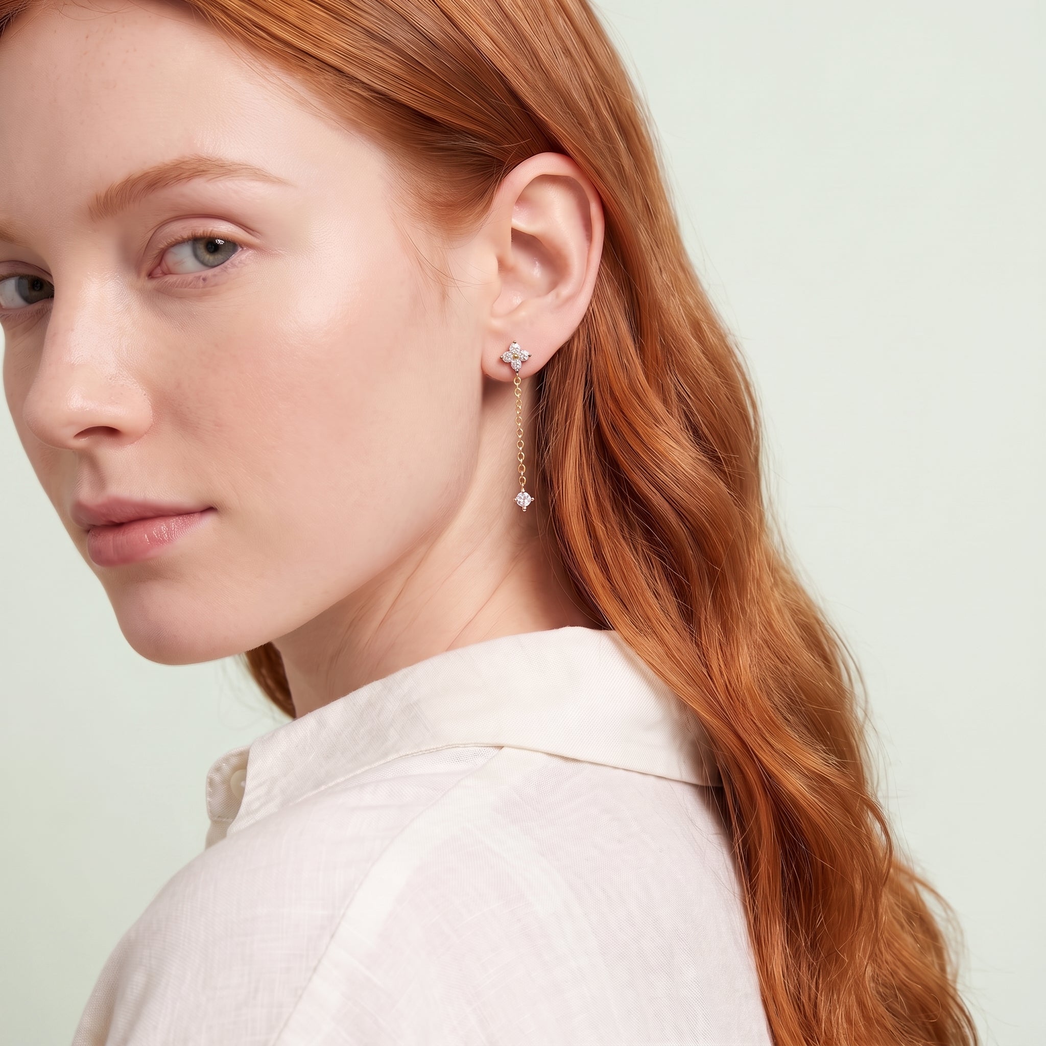 Red-haired woman glancing over her shoulder wearing Clarisse clover drop earring and ivory shirt