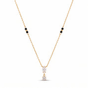 Gold crystal drop necklace laid out on a white background