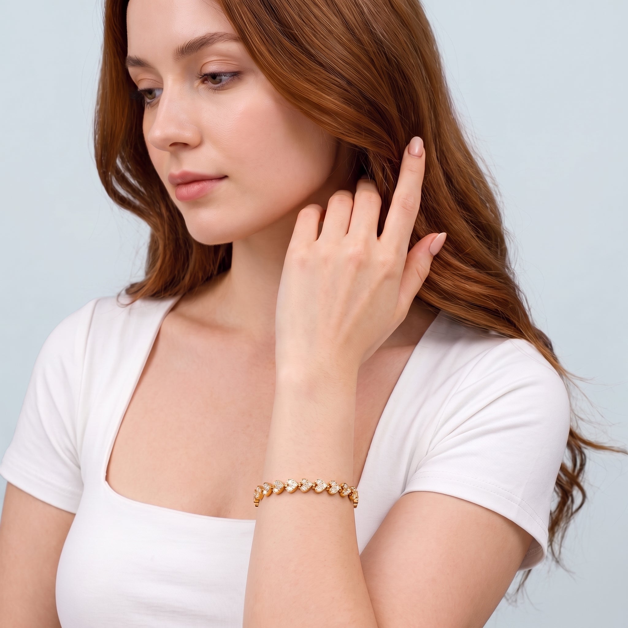 Woman sweeping auburn hair wearing Coralie gold heart tennis bracelet