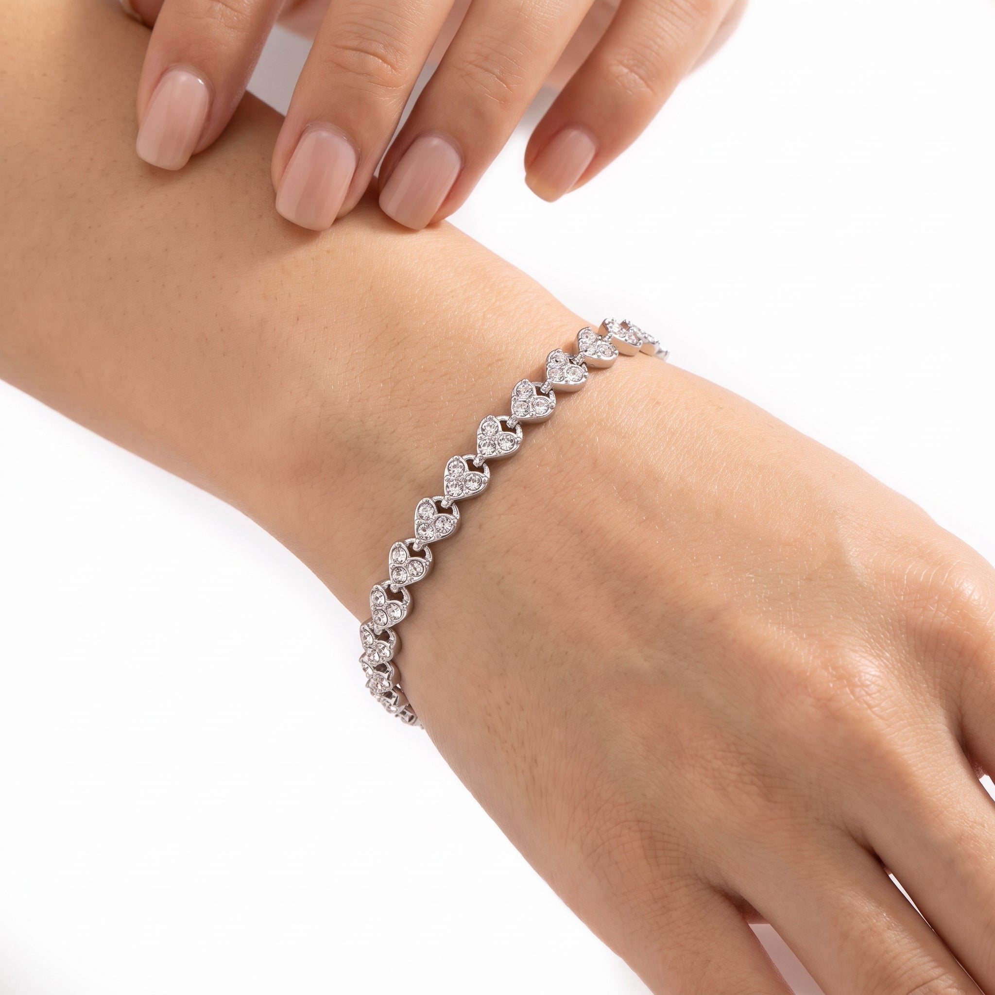 Wrist wearing Navalli silver heart tennis bracelet Coralie with clear crystals