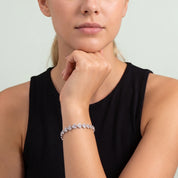 Woman resting her chin on her hand wearing Coralie silver heart bracelet