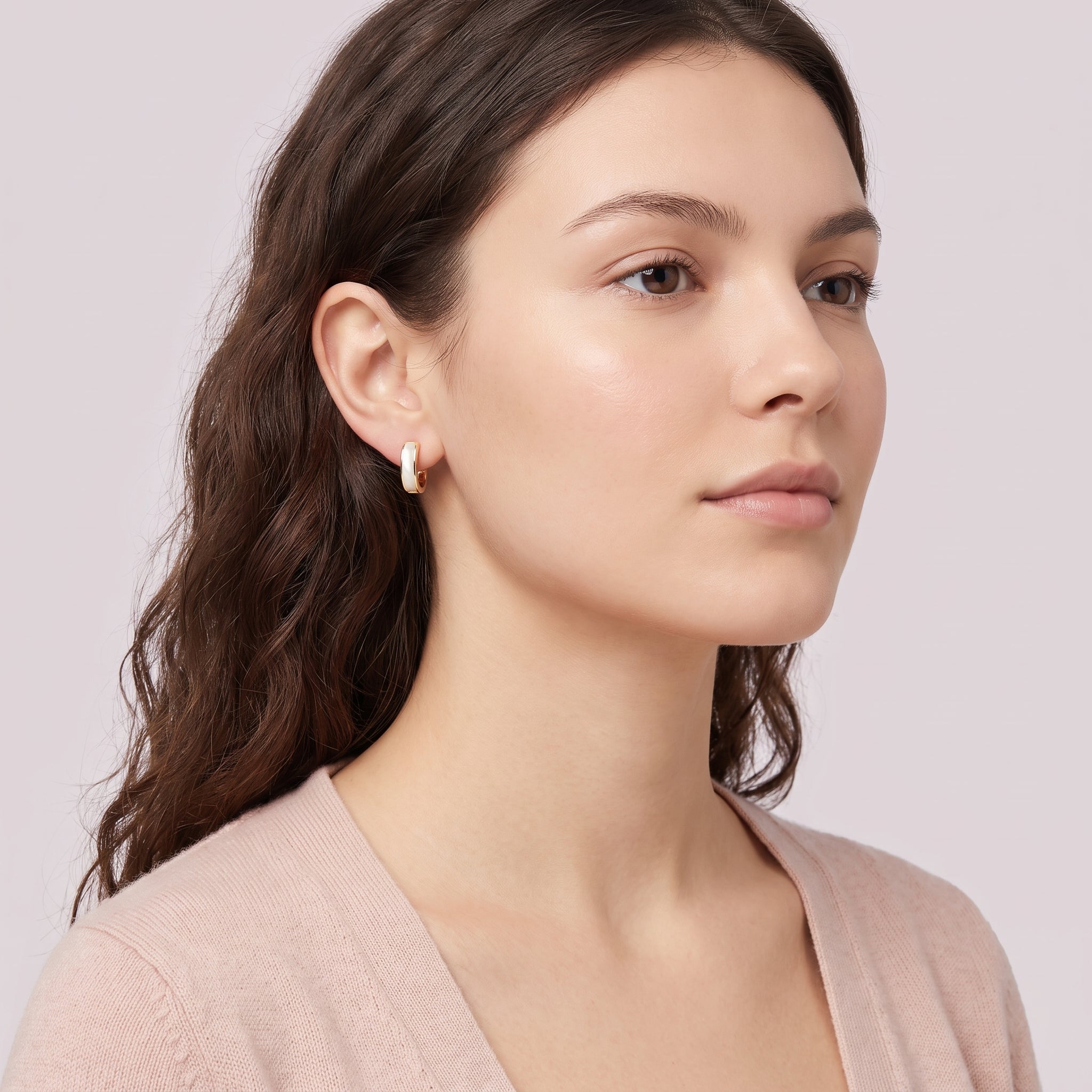 Gold square huggie earring worn with a blush cardigan