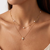 Woman wearing Estelle gold pearl star necklace with a satin slip dress