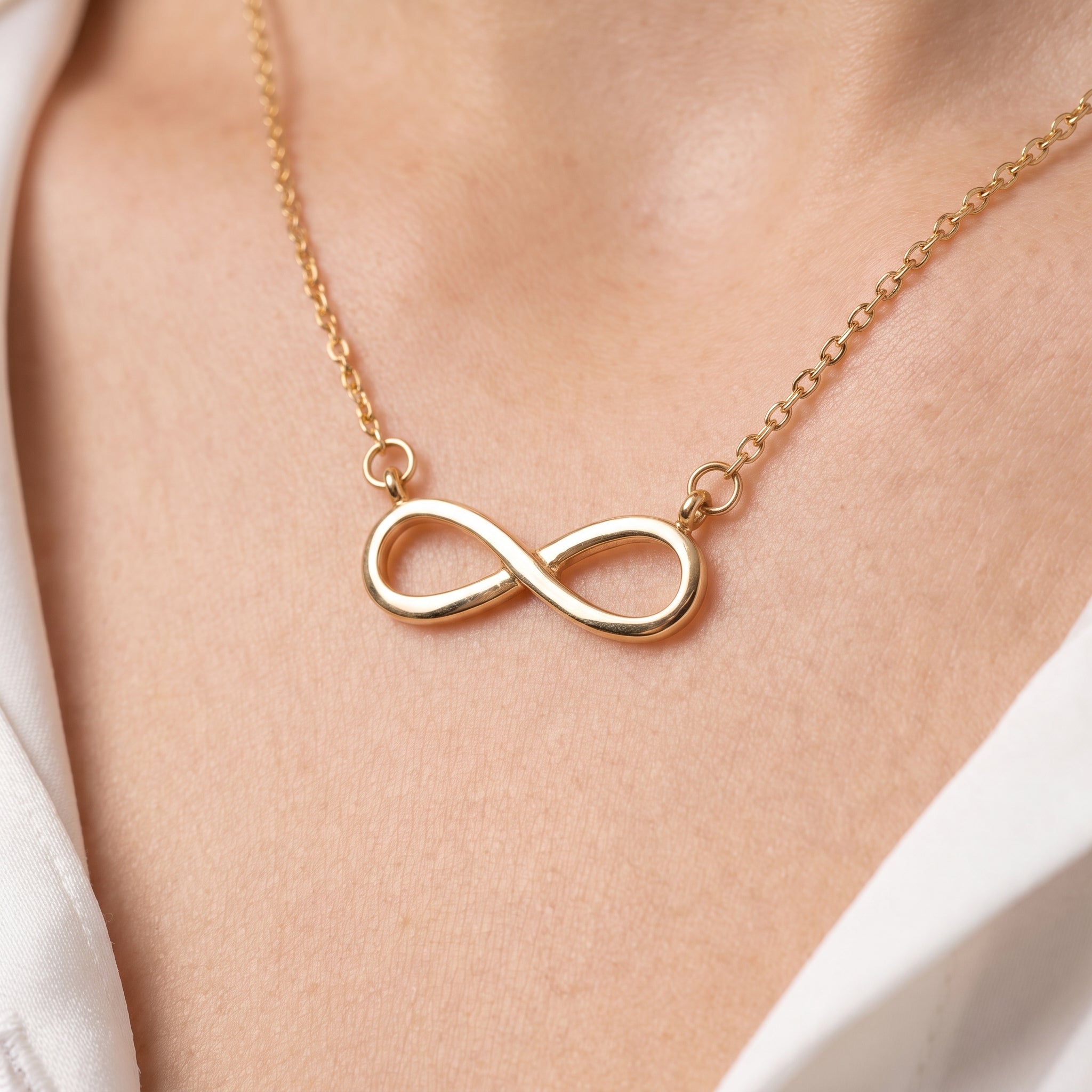 Gold infinity necklace, close-up of the polished infinity on skin