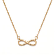 Gold infinity necklace laid out on a white background