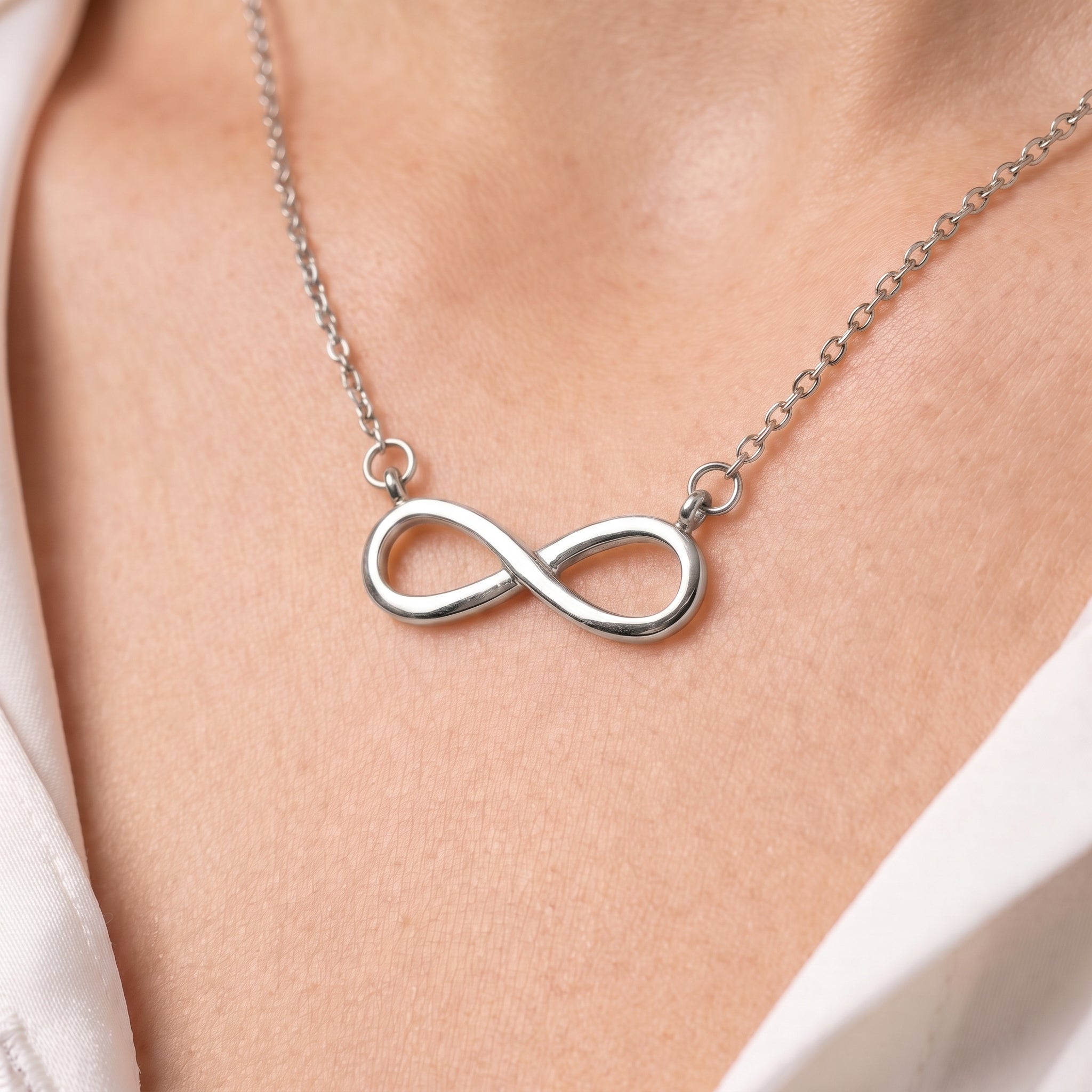Silver infinity necklace, close-up of the polished infinity on skin