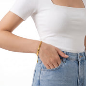 Gold chain bracelet with the hand in a jeans pocket