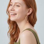 Gold clover hoop earring in a laughing portrait