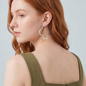 Silver clover hoop earring seen over the shoulder, olive dress