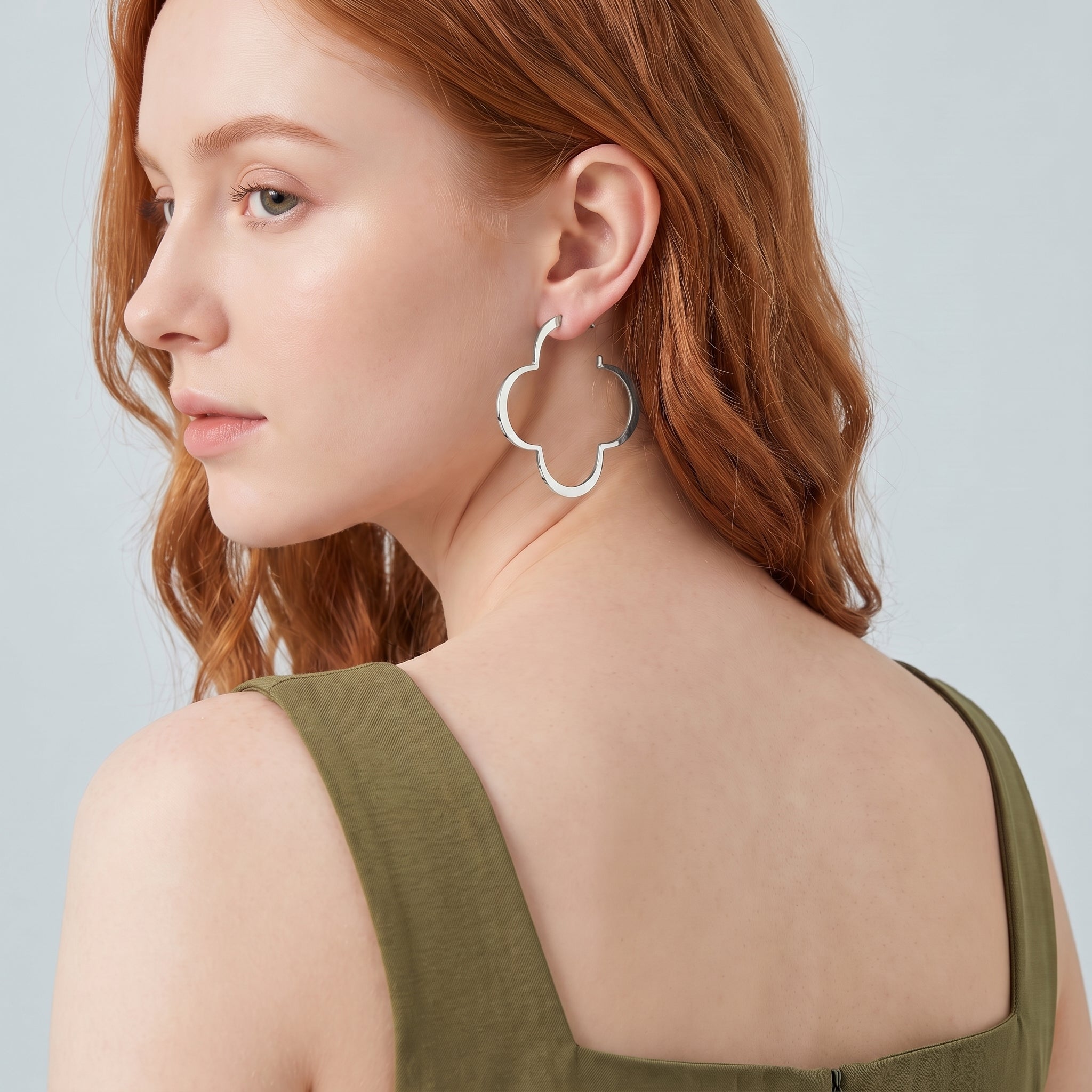 Silver clover hoop earring seen over the shoulder, olive dress